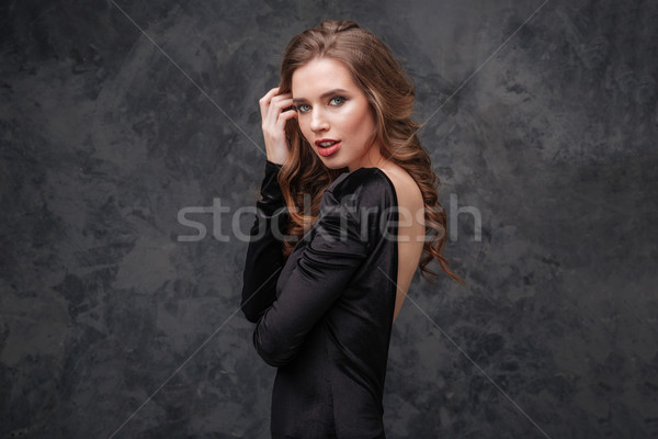 Attractive tender young woman in black dress with open back Stock photo © deandrobot