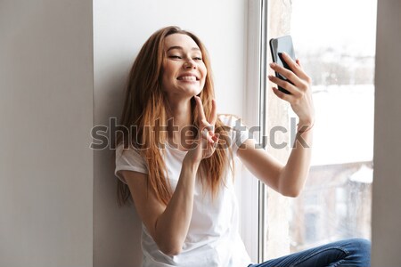 Laughing woman in towel dries hair with hairdryer Stock photo © deandrobot