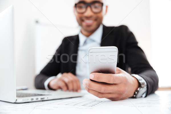Happy young businessman using mobile phone while working Stock photo © deandrobot