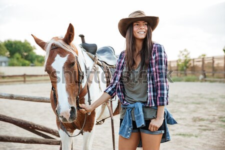 Smiling woman cowgirl riding a horse outdoors Stock photo © deandrobot