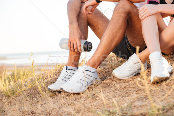 Cropped image of sports couple resting while sitting on ground Stock photo © deandrobot