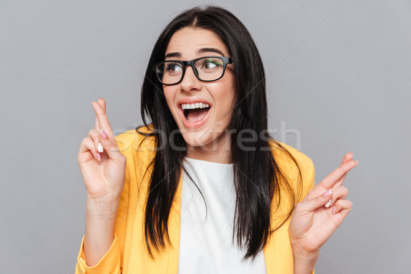 Woman crossed fingers over grey background Stock photo © deandrobot