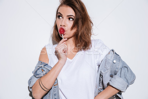 Thoughtful lady eating candy. Stock photo © deandrobot