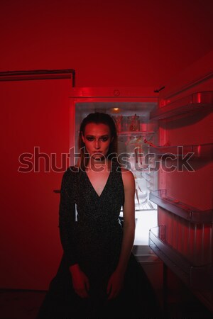 Vertical image of sensual woman sitting near fridge Stock photo © deandrobot