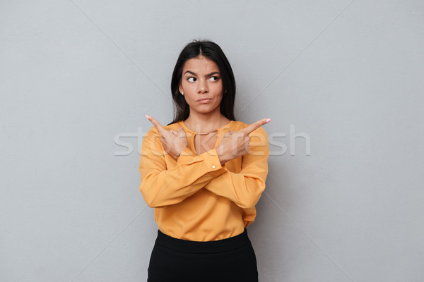 Young brunette business woman pointing sideways with two hands Stock photo © deandrobot