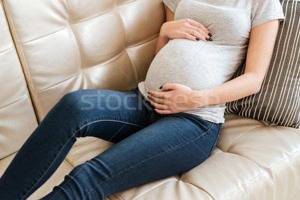 Pregnant young woman lying on couch at home Stock photo © deandrobot