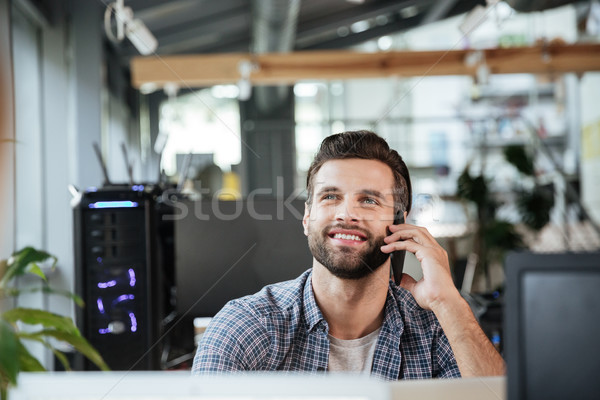 Man in office coworking while talking by mobile phone. Stock photo © deandrobot