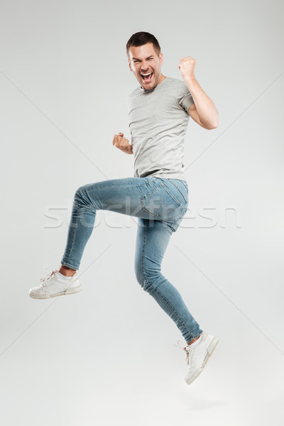 Man make winner gesture. Looking at camera jumping. Stock photo © deandrobot