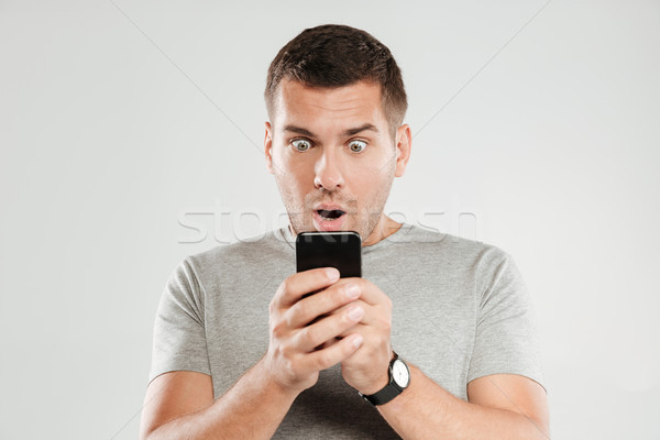 Shocked man chatting by mobile phone. Stock photo © deandrobot