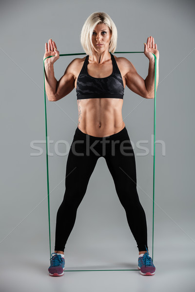 Full length photo of serious fitness woman stretching with elast Stock photo © deandrobot