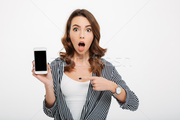Portrait of a shocked casual girl pointing finger Stock photo © deandrobot