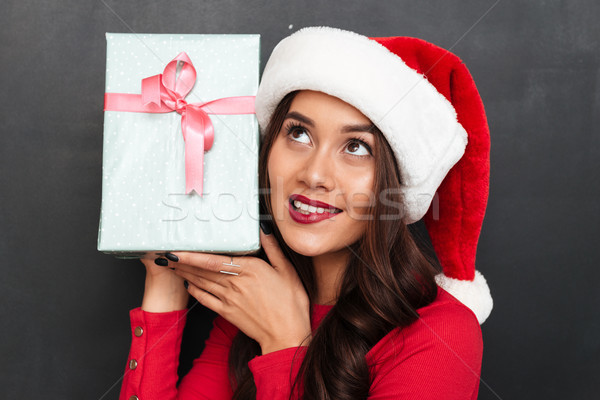 Intrigued smiling brunette woman in red blouse and christmas hat Stock photo © deandrobot