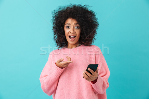 Image of american curly woman in pink shirt reacting emotionally Stock photo © deandrobot