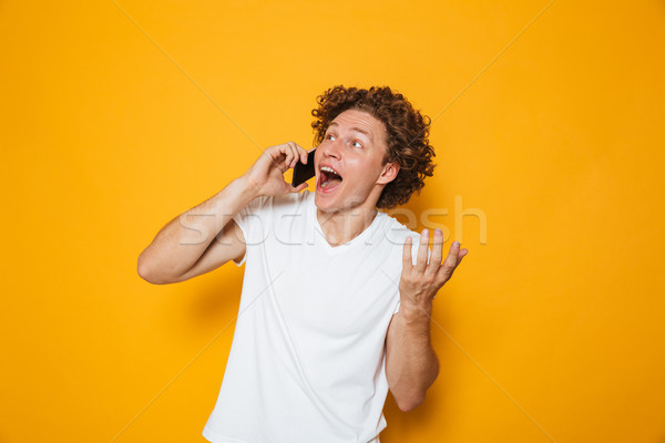 Photo of happy young guy with curly hair shouting and talking on Stock photo © deandrobot
