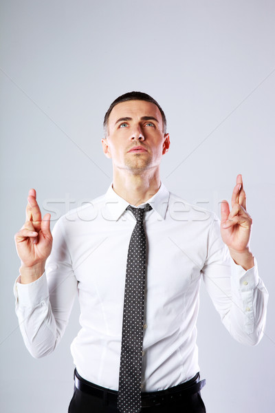 Businessman making a wish and looking up over gray background Stock photo © deandrobot