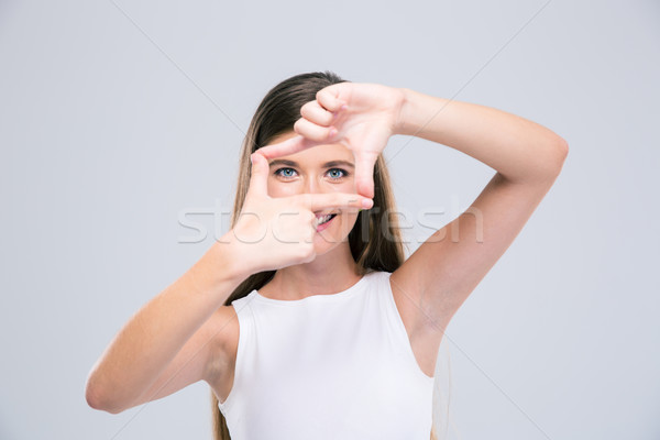 Happy female teenager looking at camera through frame gesture Stock photo © deandrobot