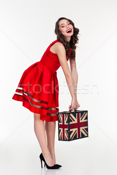 Cheerful attractive curly woman holding vintage suitcase with british flag Stock photo © deandrobot