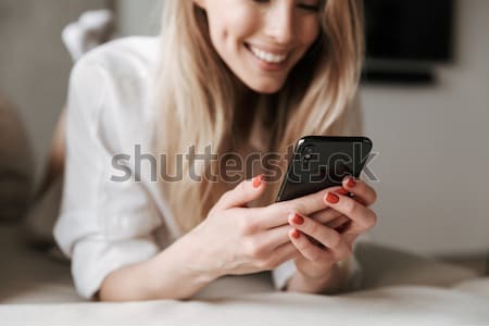 Closeup of mobile phone used by happy young woman Stock photo © deandrobot