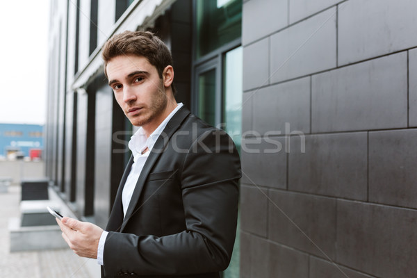 Side view of business man with phone near the office Stock photo © deandrobot