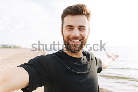 Young man in casual clothes walking at the beach Stock photo © deandrobot