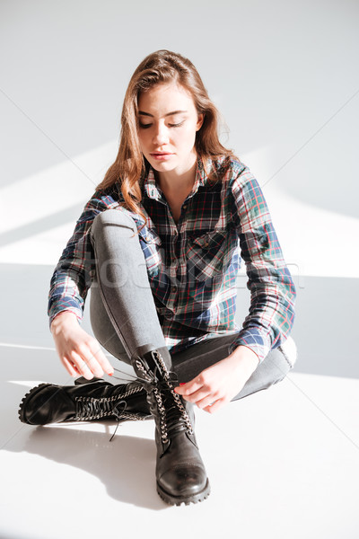 Young lady sitting on floor at studio and tie laces Stock photo © deandrobot