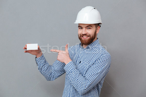 Cheerful bearded builder holding copyspace business card Stock photo © deandrobot