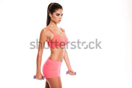 Stock photo: Portrait of a pretty young sportswoman doing exercises with dumbbells