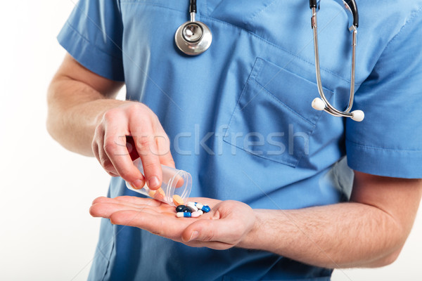 Male doctors pouring pills froma a bottle on his palm Stock photo © deandrobot