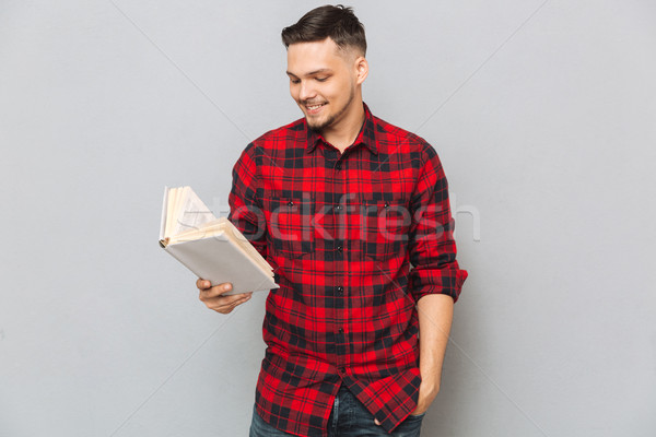 Smiling man reading book in studio Stock photo © deandrobot