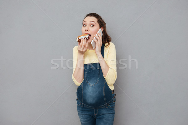 Pregnant happy woman eating eclair and talking by phone Stock photo © deandrobot