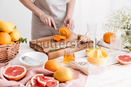 Woman standing near table with citruses and holding honey. Stock photo © deandrobot