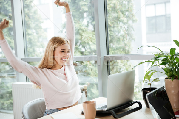 Cheerful lady in office coworking talking with friends by laptop. Stock photo © deandrobot