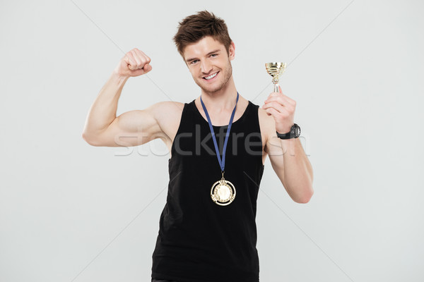 Stock photo: Handsome young sportsman with medal and reward
