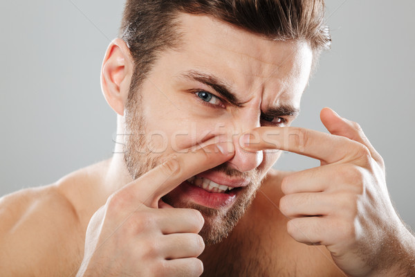 Close up portrait of a man squeezing pimple on his face Stock photo © deandrobot