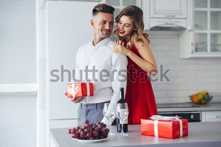 Confident beautiful man winking to camera while hug his lovely woman Stock photo © deandrobot