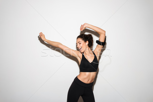 Blijde gekruld brunette fitness vrouw luisteren muziek Stockfoto © deandrobot