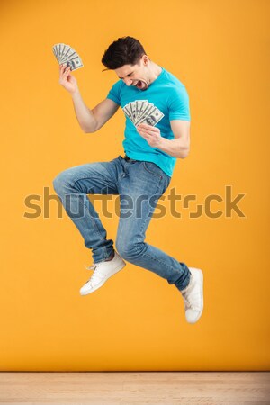 Emotional funny young woman jumping listening music. Stock photo © deandrobot