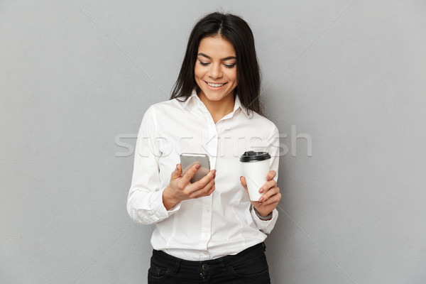 Photo of successful woman in formal wear standing with smartphon Stock photo © deandrobot