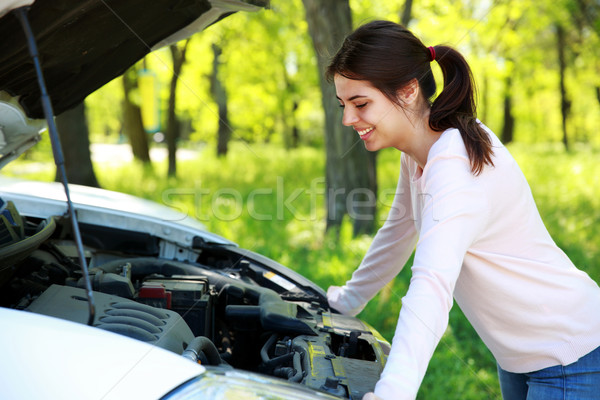 Happy woman looks under hood car background green park Stock photo © deandrobot