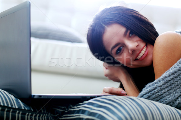 Portrait of a beautiful woman lying on the floor with laptop at home Stock photo © deandrobot