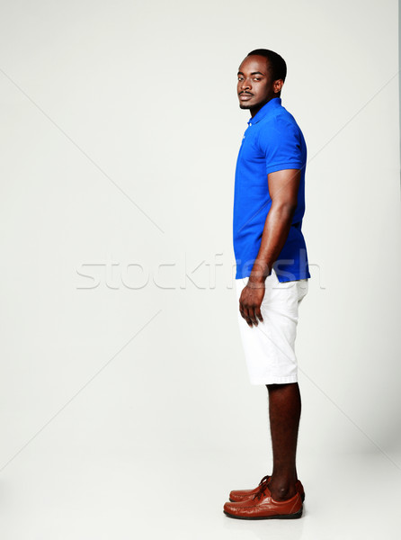 Side view portrait of african man standing on gray background Stock photo © deandrobot