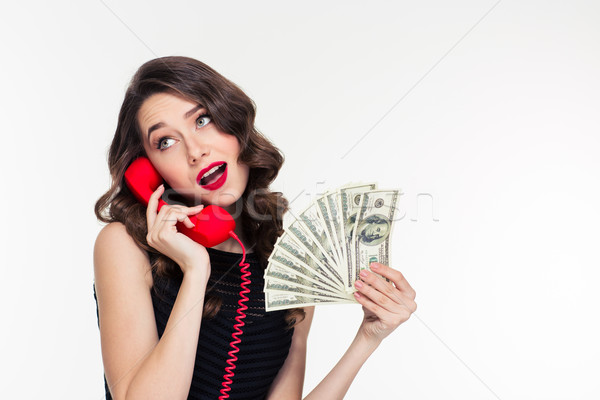 Attractive joyful curly female holding money and talking on telephone Stock photo © deandrobot