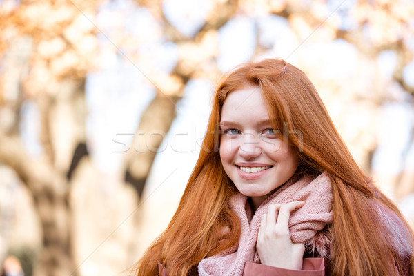 Smiling redhead woman looking at camera outdoors Stock photo © deandrobot