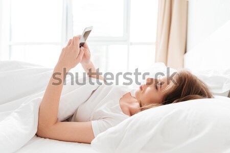 Woman lying on the bed with raised legs up Stock photo © deandrobot