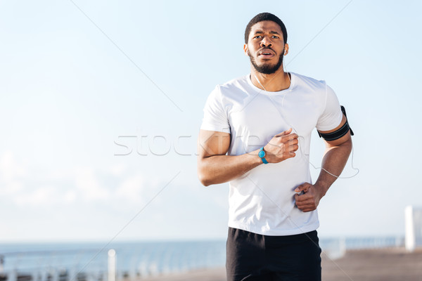 Serious sportsman running and listening to music outdoors Stock photo © deandrobot