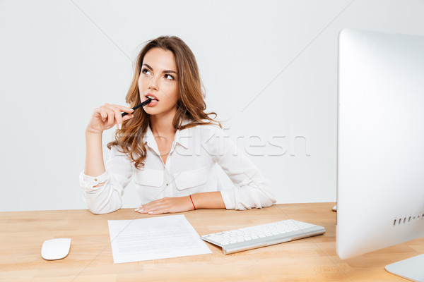 Pensive young businesswoman sitting at the office desk and thinking Stock photo © deandrobot