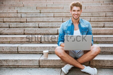 Happy cheerful student with tablet and coffee cup sitting outdoors Stock photo © deandrobot