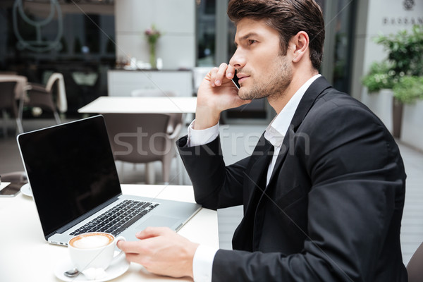 Businessman using blank screen laptop and talking on cell phone Stock photo © deandrobot