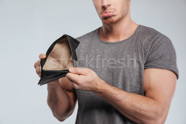 Cropped image of a sad casual man showing empty wallet Stock photo © deandrobot