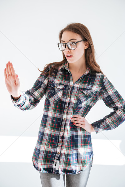 Stock photo: Serious young woman in glasses standing and showing stop gesture
